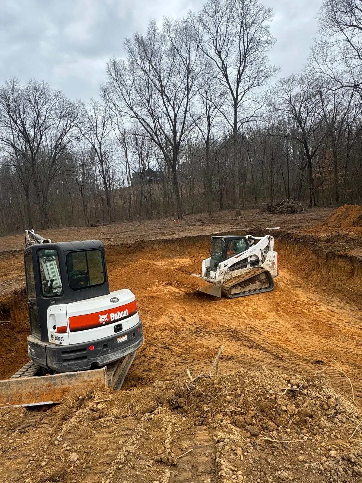 Excavator and skid steer preparing a cleared property.